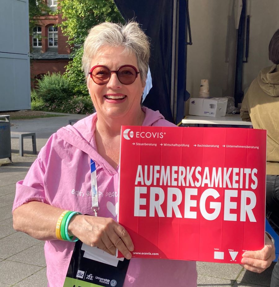 Nicole mit einem Schild mit den Worten "Aufmerksamkeitserreger"
